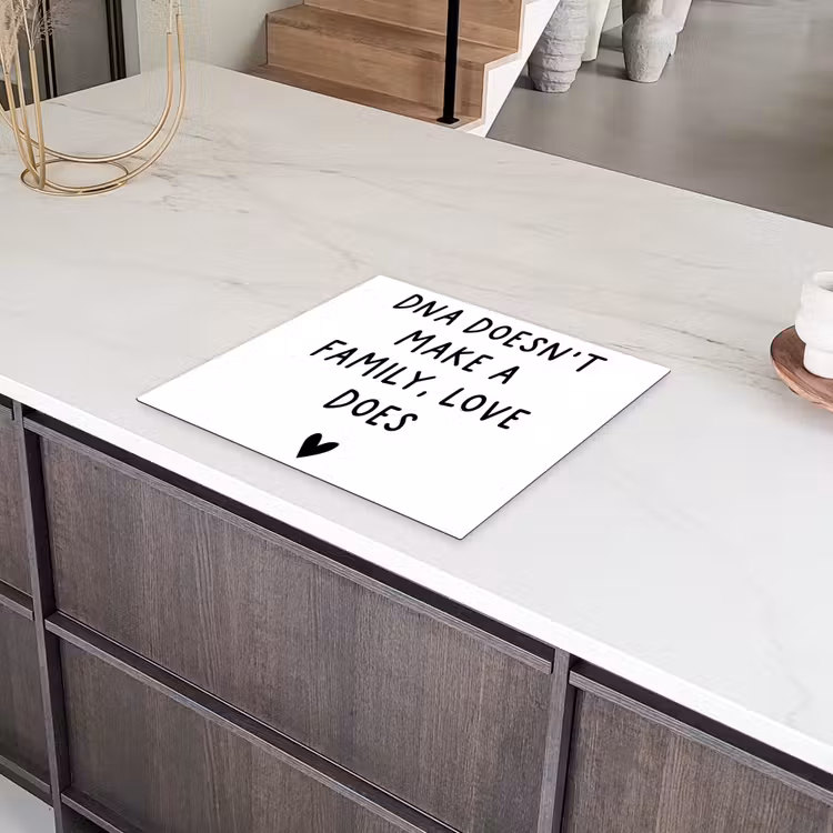 Engelse quote "DNA doesn't make a family, love does" met een hartje op een witte achtergrond Inductie beschermer vinyl 3mm middel -sfeer8