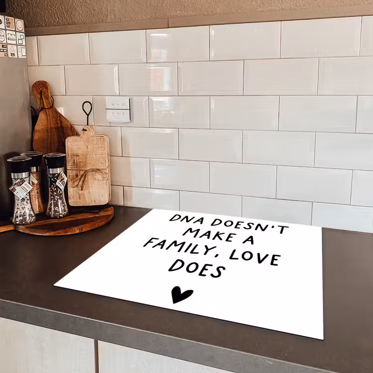 Engelse quote "DNA doesn't make a family, love does" met een hartje op een witte achtergrond Inductie beschermer vinyl 3mm middel -sfeer3